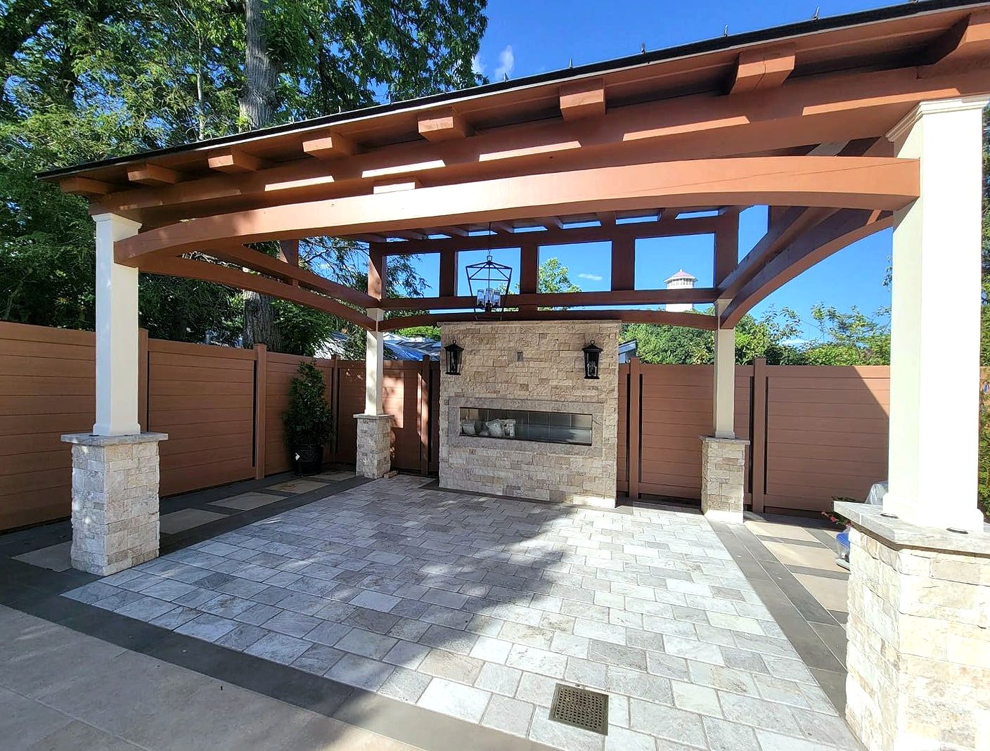 Timber pavilion with stone fireplace over paver patio