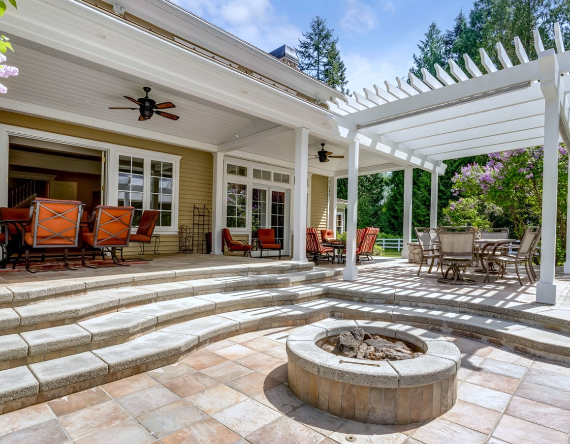 Patio with stone steps, fire pit and white pergola beside house